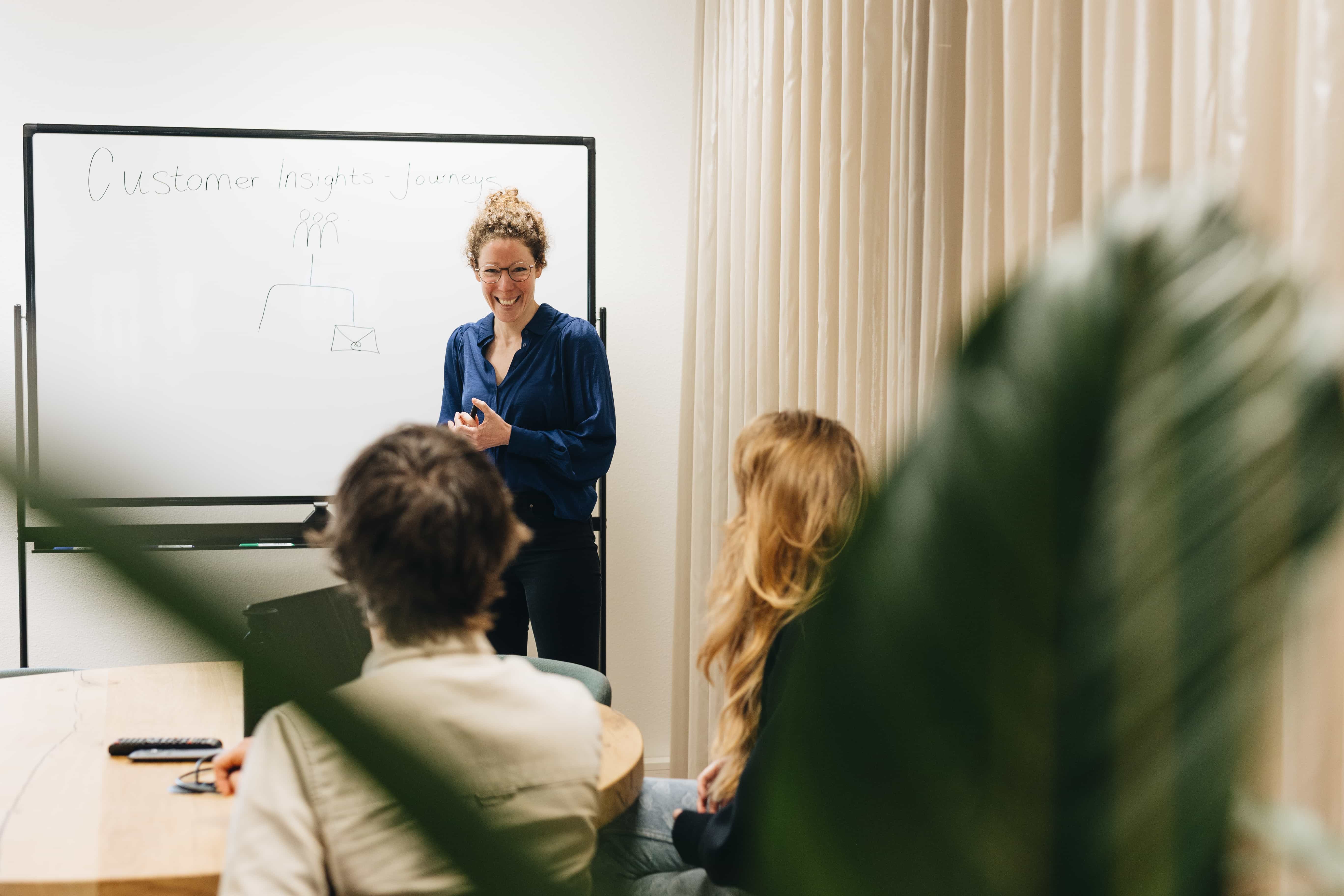 Groep mensen in een moderne kantoorruimte tijdens een overleg aan tafel met laptop en tablet