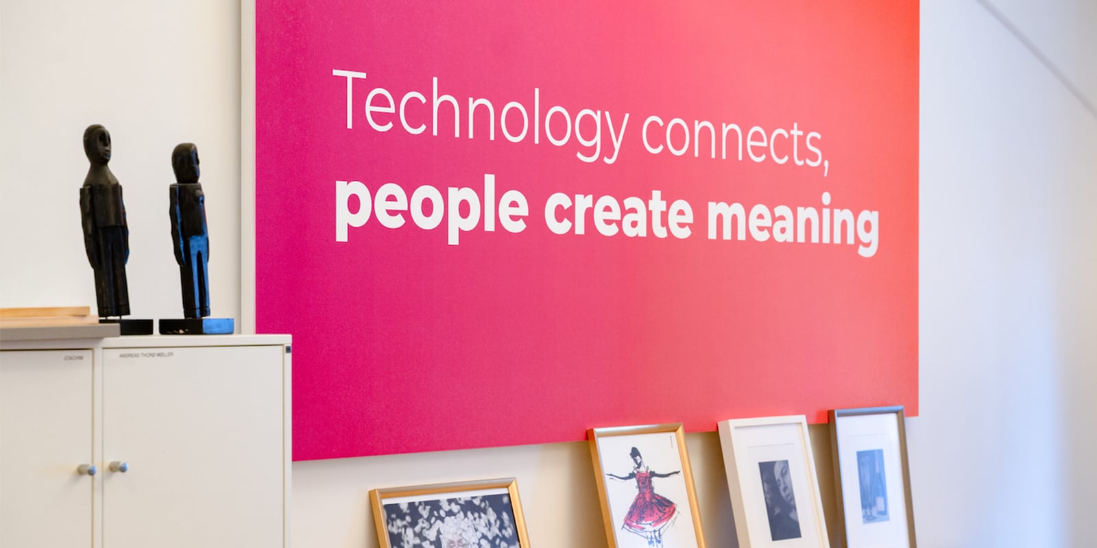 Et pink og orange lærred på en væg med teksten "Technology connects, people create meaning"