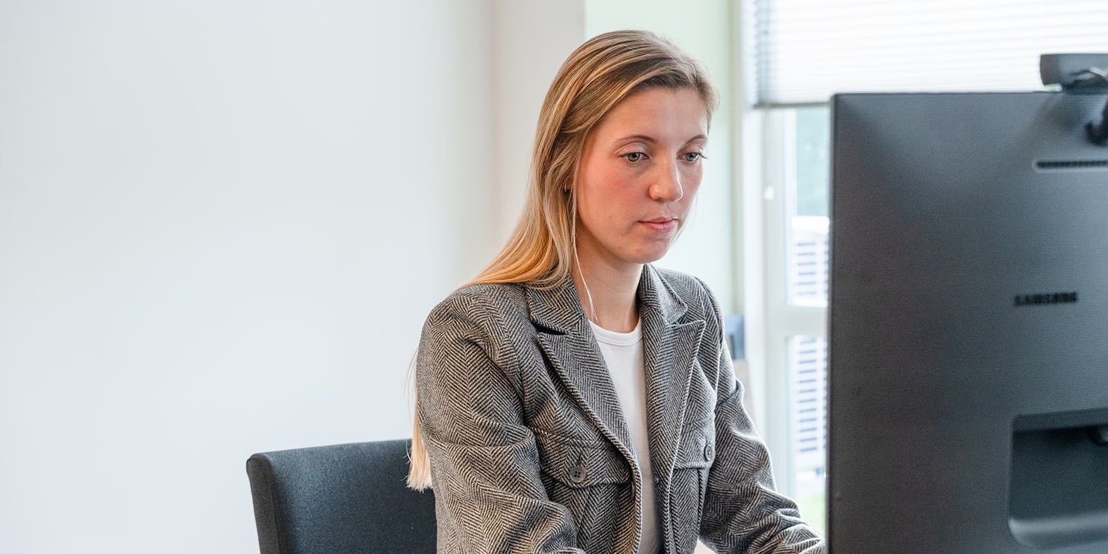 Kvinde sidder bag en computerskærm og fokuserer på sit arbejde