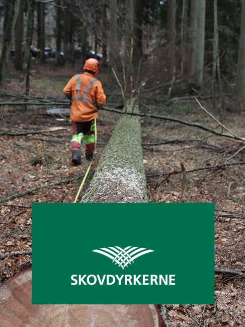 Mand der saver et faldent træ over med "Skovdyrkerne" logo på